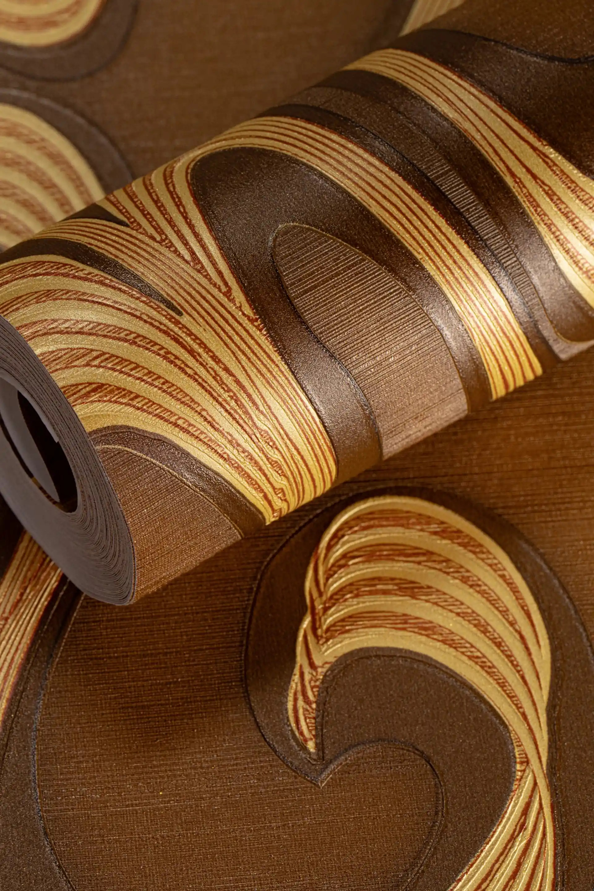 Rolled brown and gold wallpaper featuring bold retro swirl pattern with metallic finish on textured base