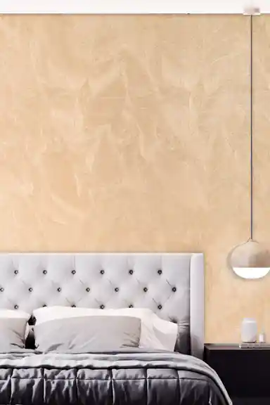 Embossed beige-gold wallpaper in a modern bedroom with a tufted grey headboard and pendant light