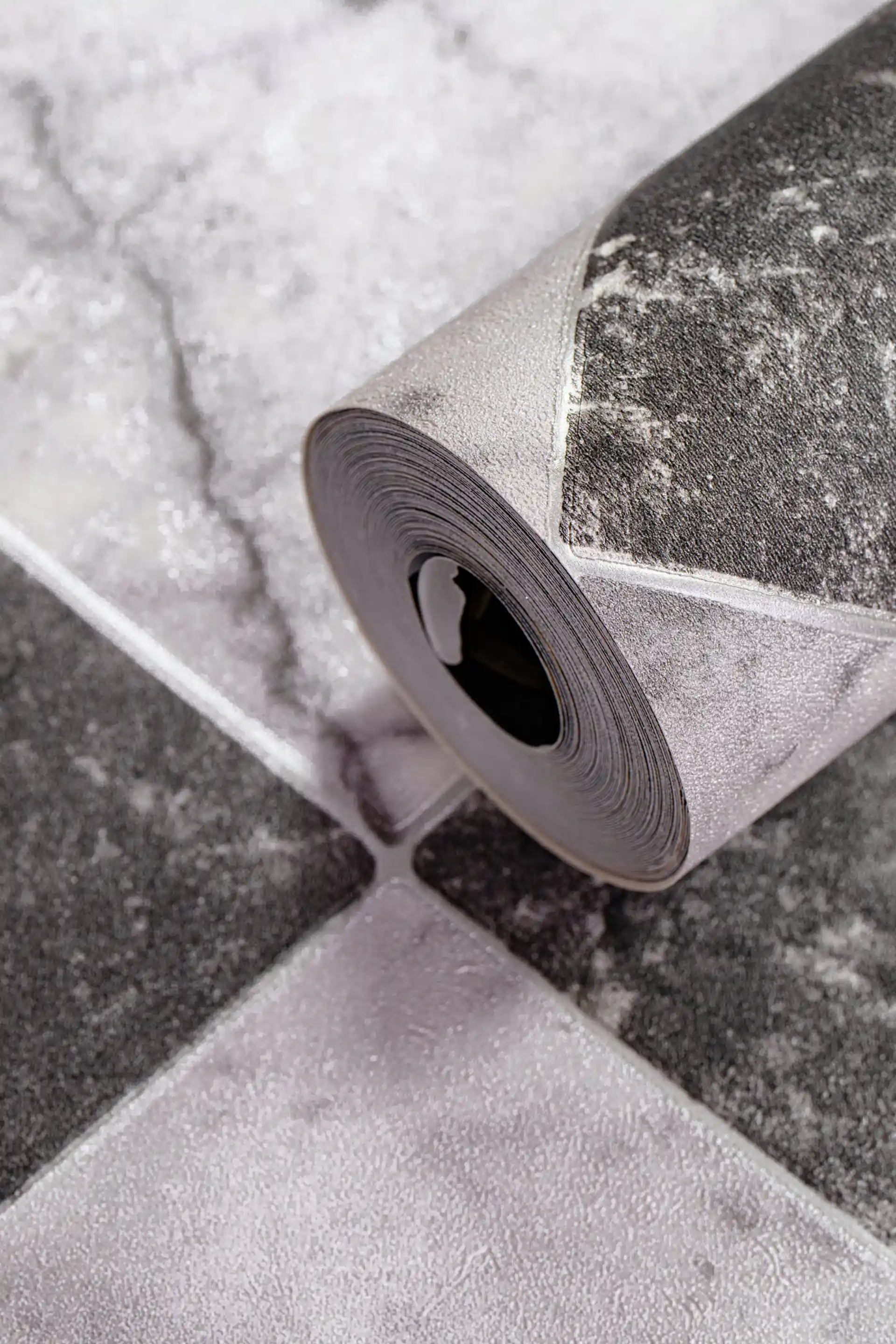 Rolled black and white marble checker wallpaper showing diamond tile pattern with realistic stone texture