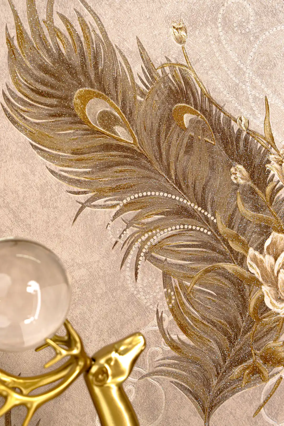 Detailed view of embossed peacock feather pattern with gold accents and a crystal orb on beige wallpaper