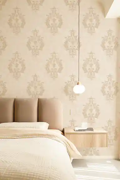 Cream damask wallpaper installed in a serene bedroom with upholstered bed and pendant light