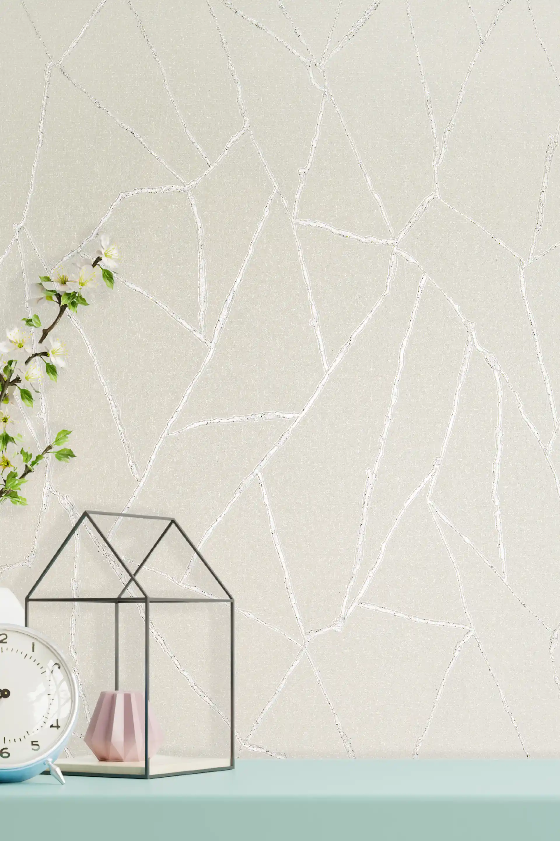 Off-white textured wallpaper with shimmering silver abstract vein lines displayed on a styled shelf