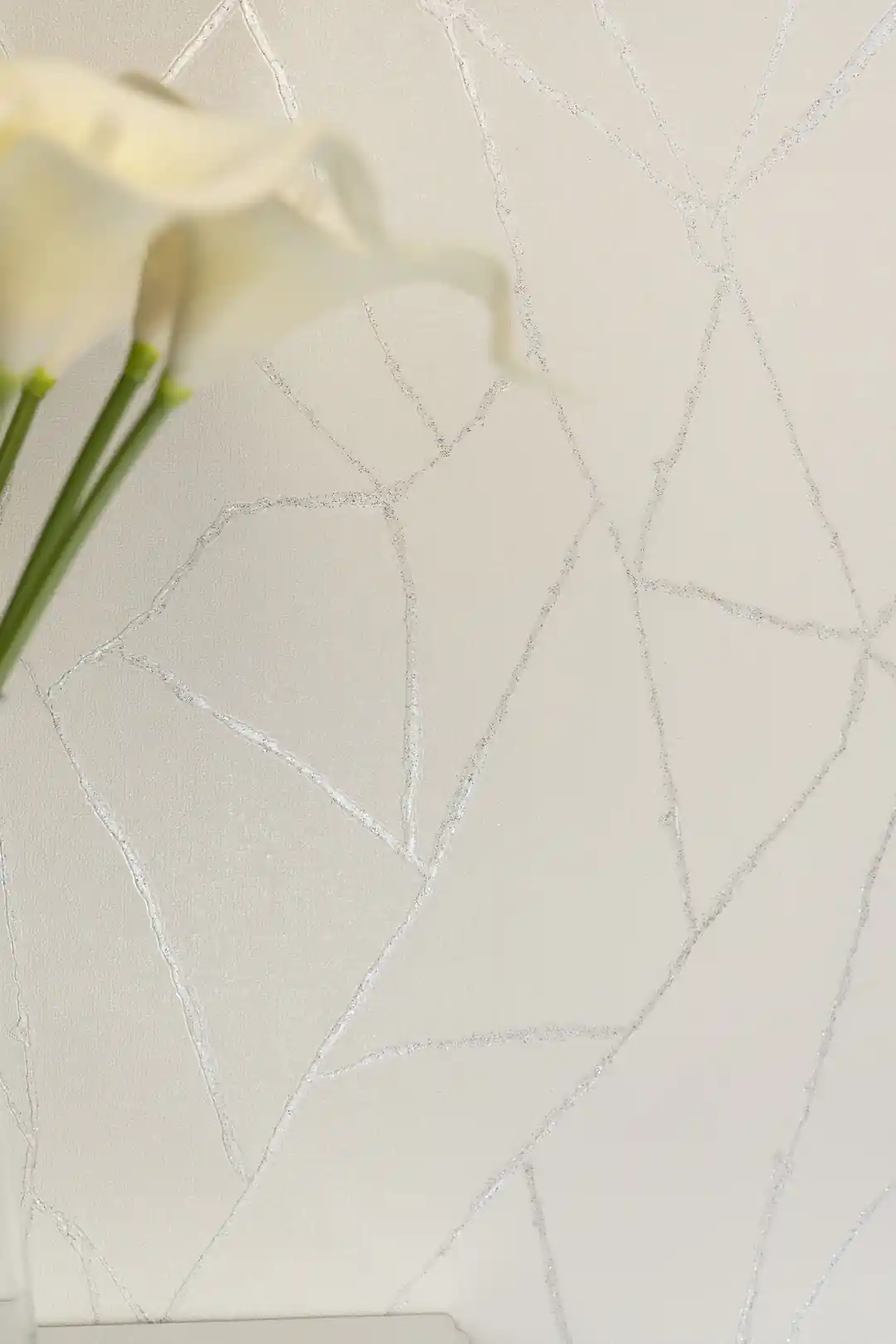 Close-up of off-white wallpaper with white calla lilies highlighting the subtle silver vein pattern