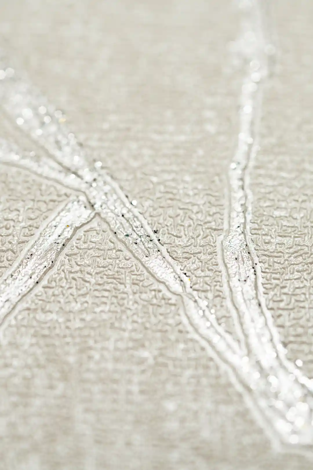 Extreme macro of shimmering silver abstract vein texture showing raised glitter lines on off-white wallpaper