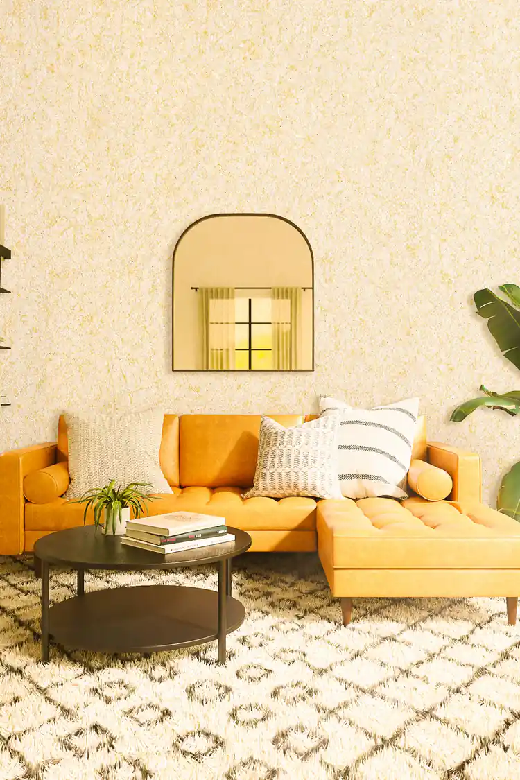 Cream silk wallpaper installed in a living room with orange sectional sofa and arched mirror