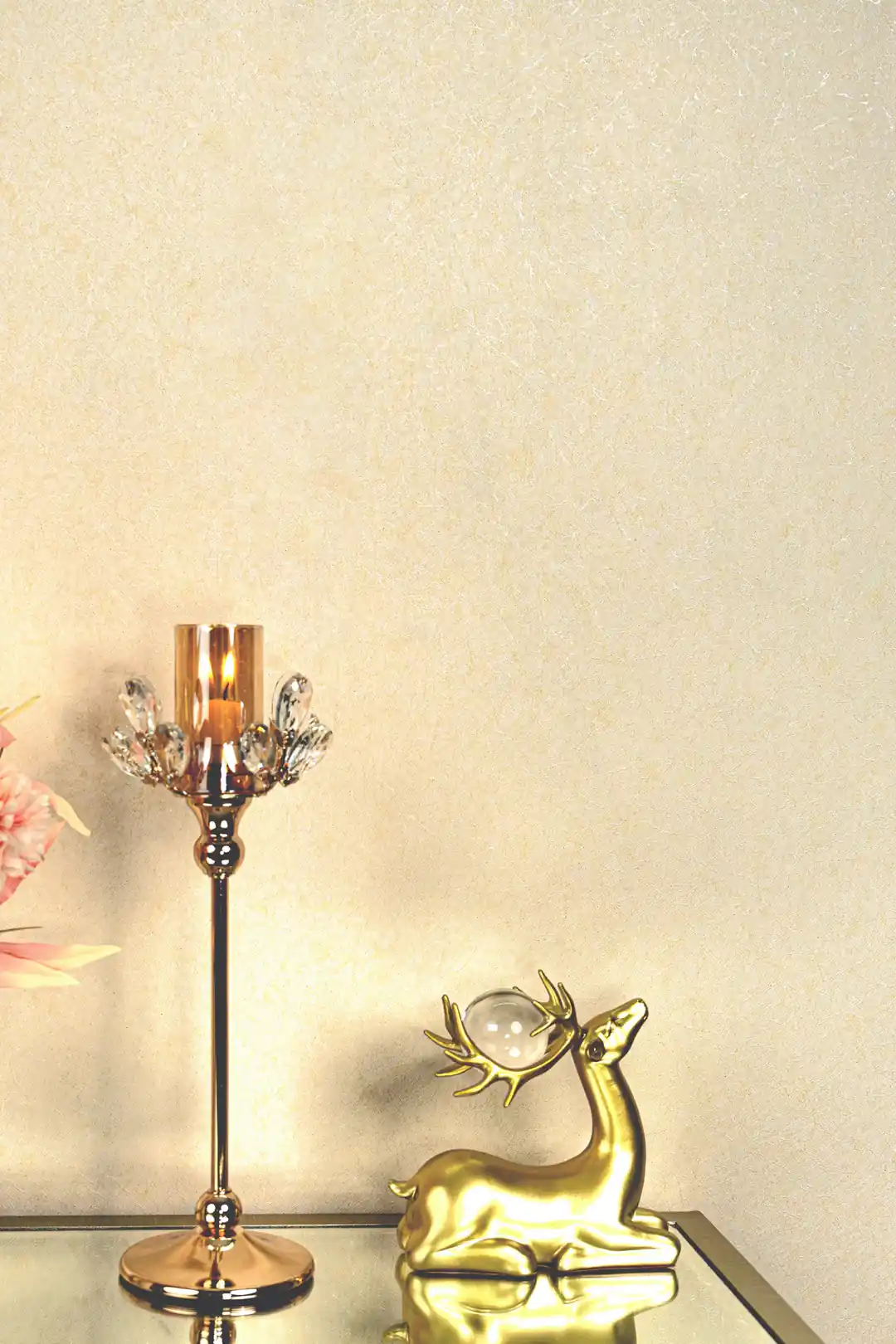 Close-up of cream silk texture wallpaper with golden deer figurine and crystal candleholder decor