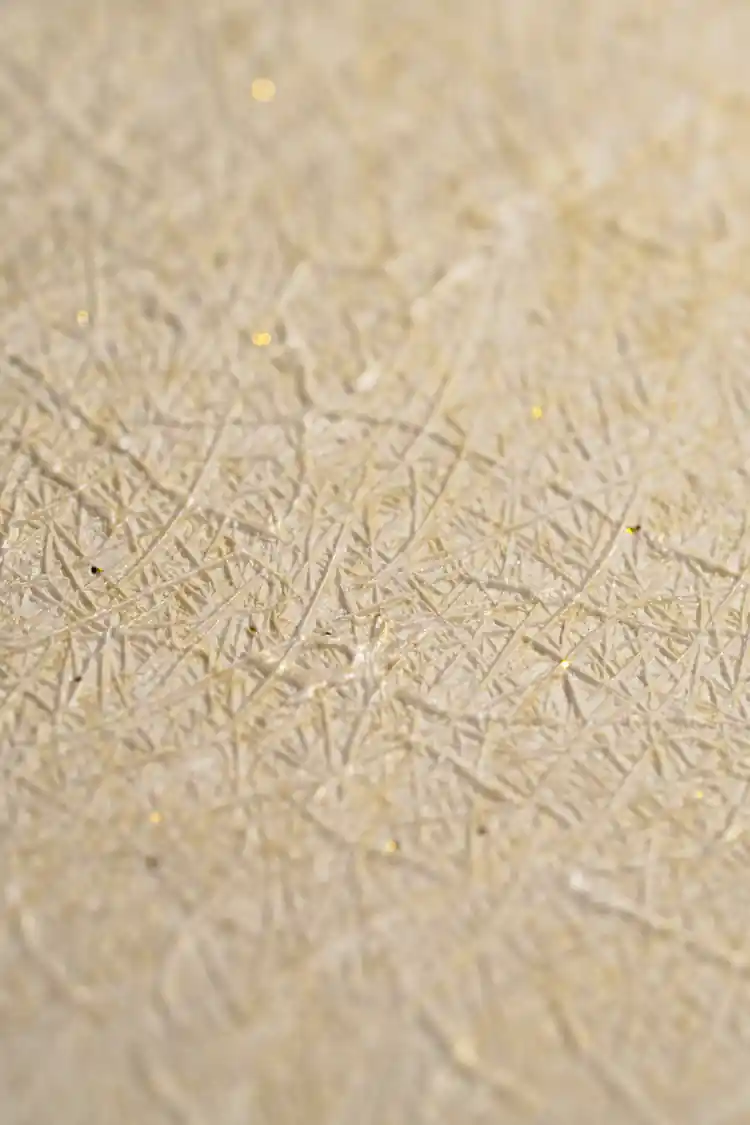 Extreme macro of cream silk wallpaper showing fine woven thread texture with golden sparkle