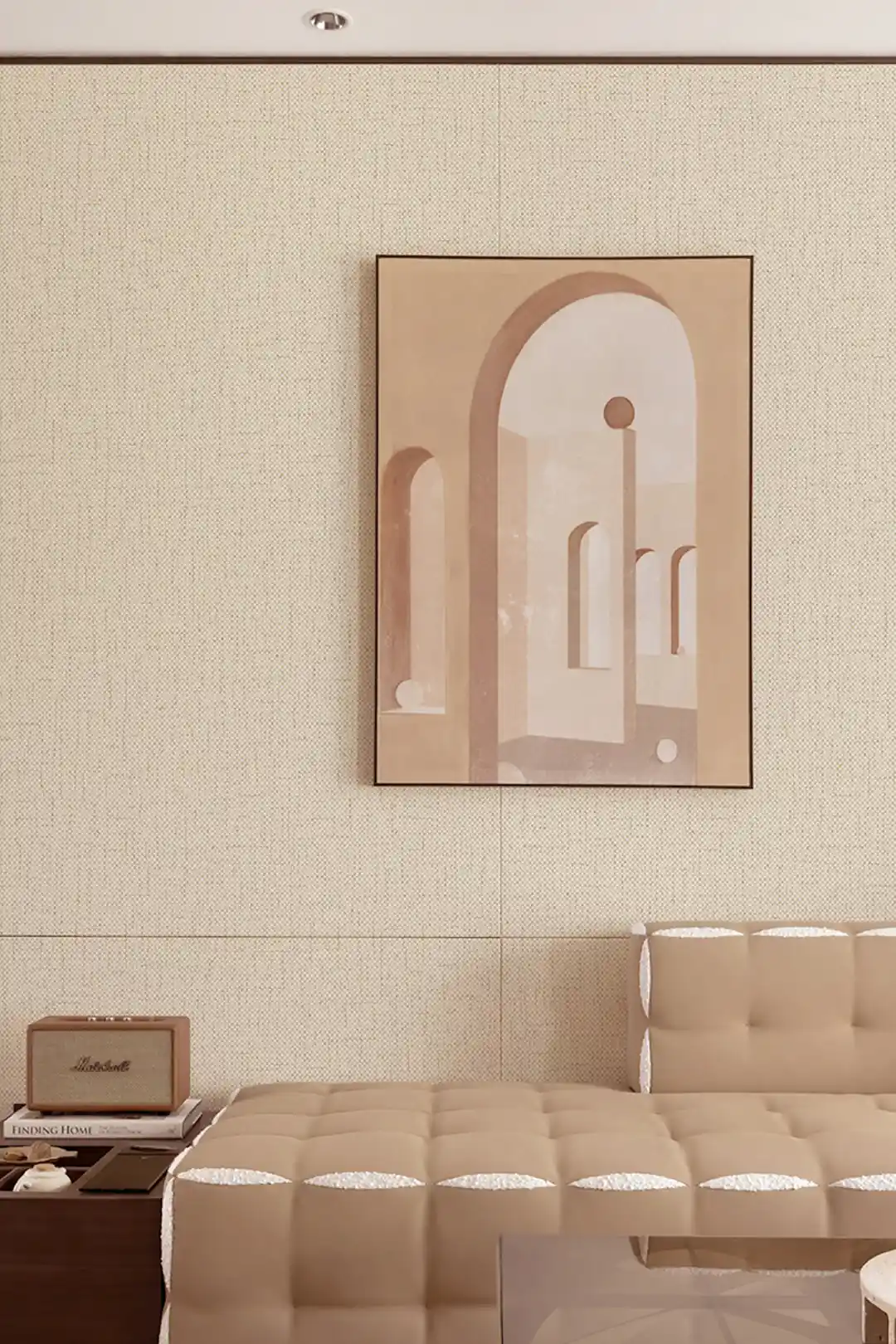 Cream grasscloth wallpaper in a bedroom setting with framed architectural art print and cream tufted daybed