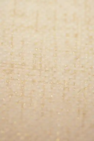 Extreme macro of cream grasscloth wallpaper showing woven dot texture with golden shimmer detail