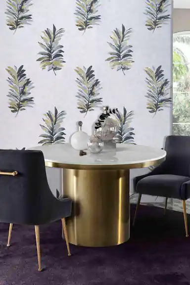 Grey fern leaf wallpaper installed in a dining room with gold pedestal table and velvet chairs