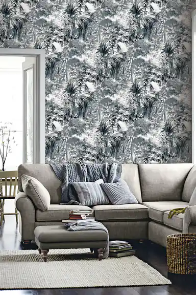 Tropical palm wallpaper installed in a living room with beige sofa, blue pillows, and woven basket