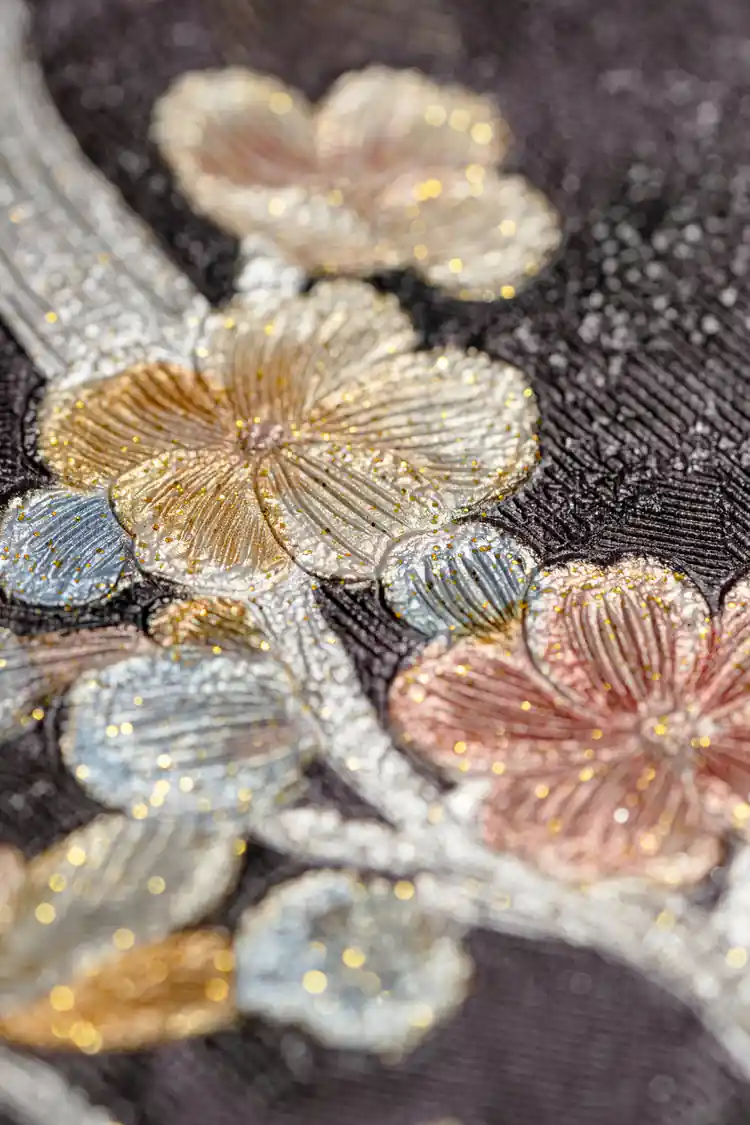 Extreme macro of embossed cherry blossom petals with gold, pink, and blue glitter on dark base