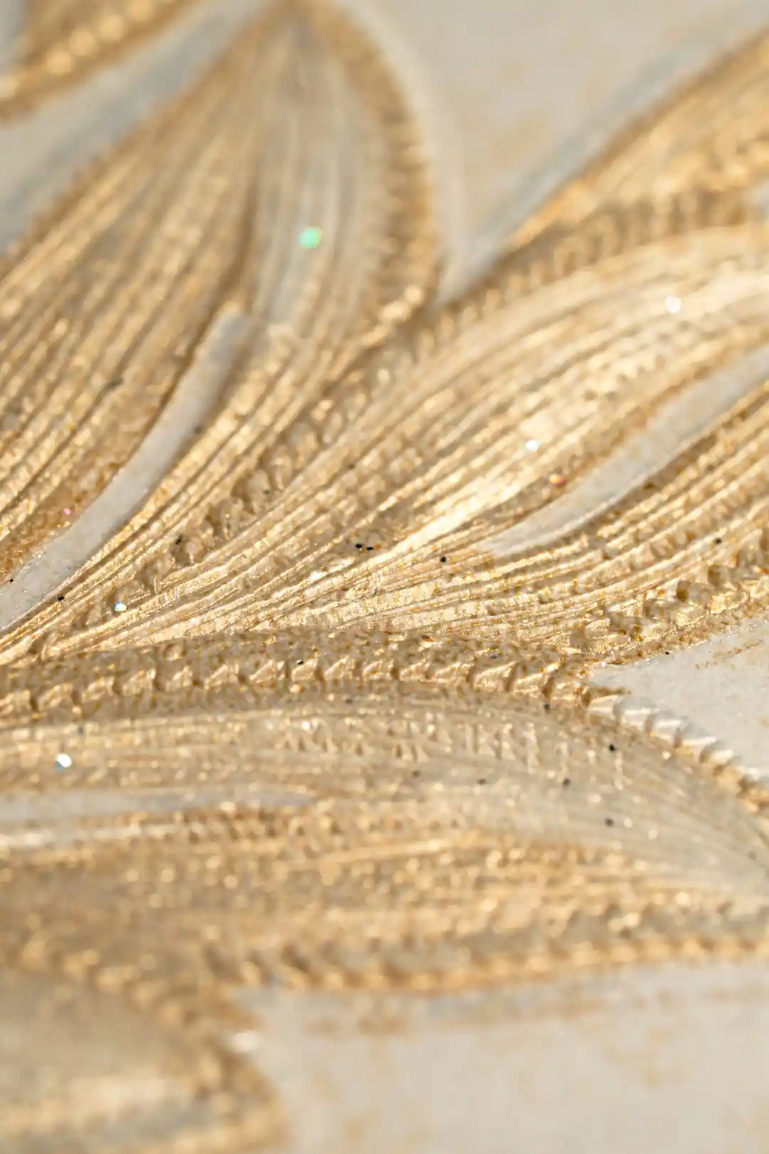 Extreme macro of embossed golden leaf texture showing raised ridges and sparkle detail