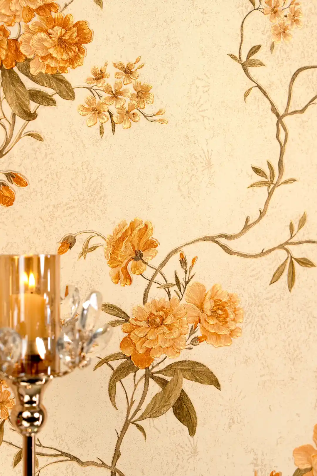 Close-up of orange peony flowers and curving vine branches on cream wallpaper with candlelight