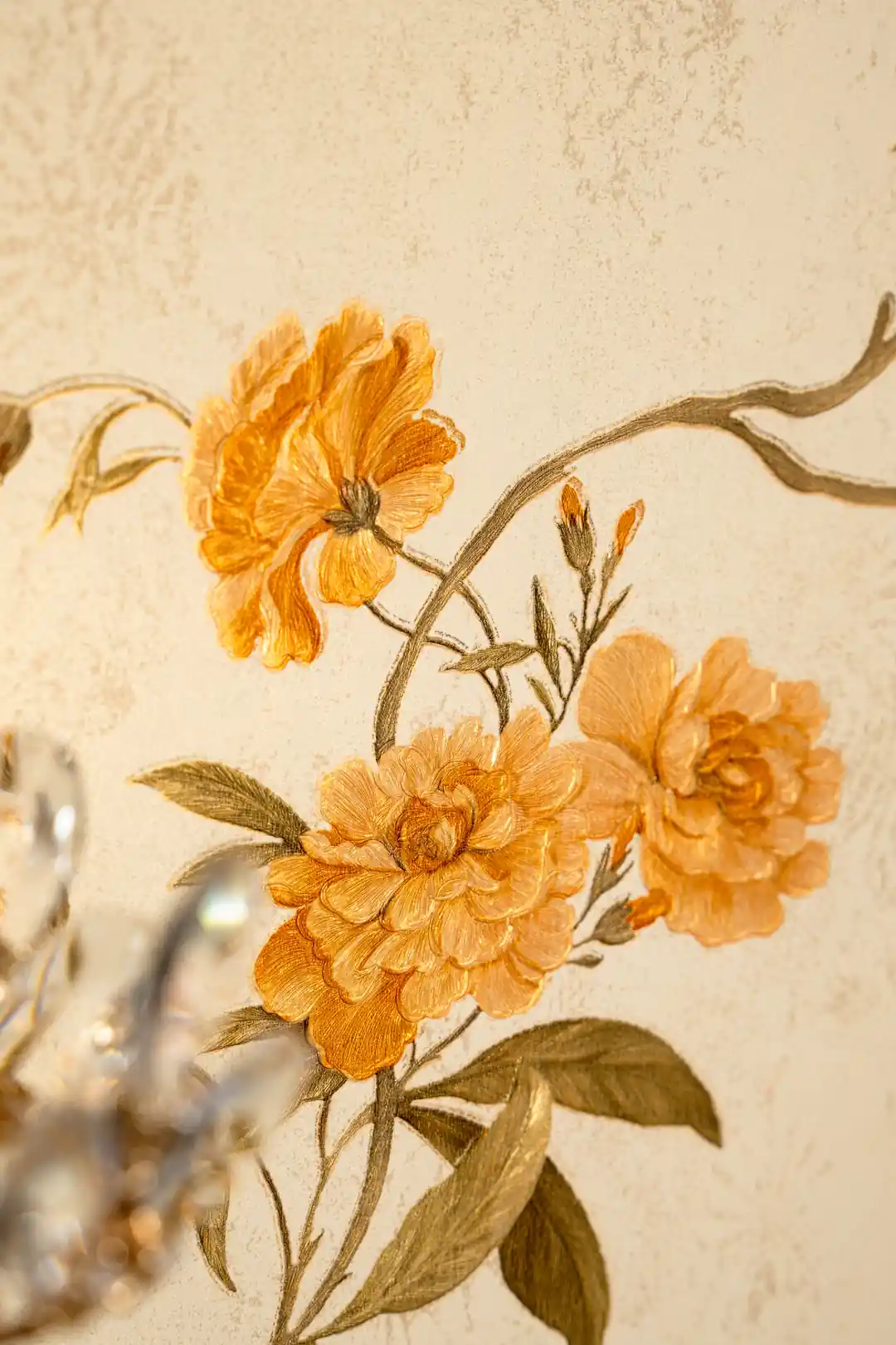 Detailed view of embossed golden orange peony cluster with olive leaves on cream wallpaper