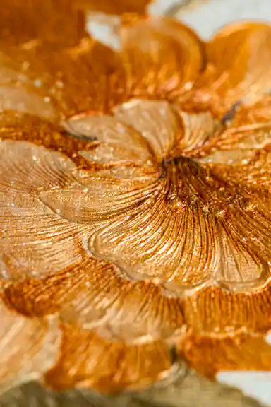 Extreme close-up of raised golden orange peony petals showing embossed shimmer texture detail