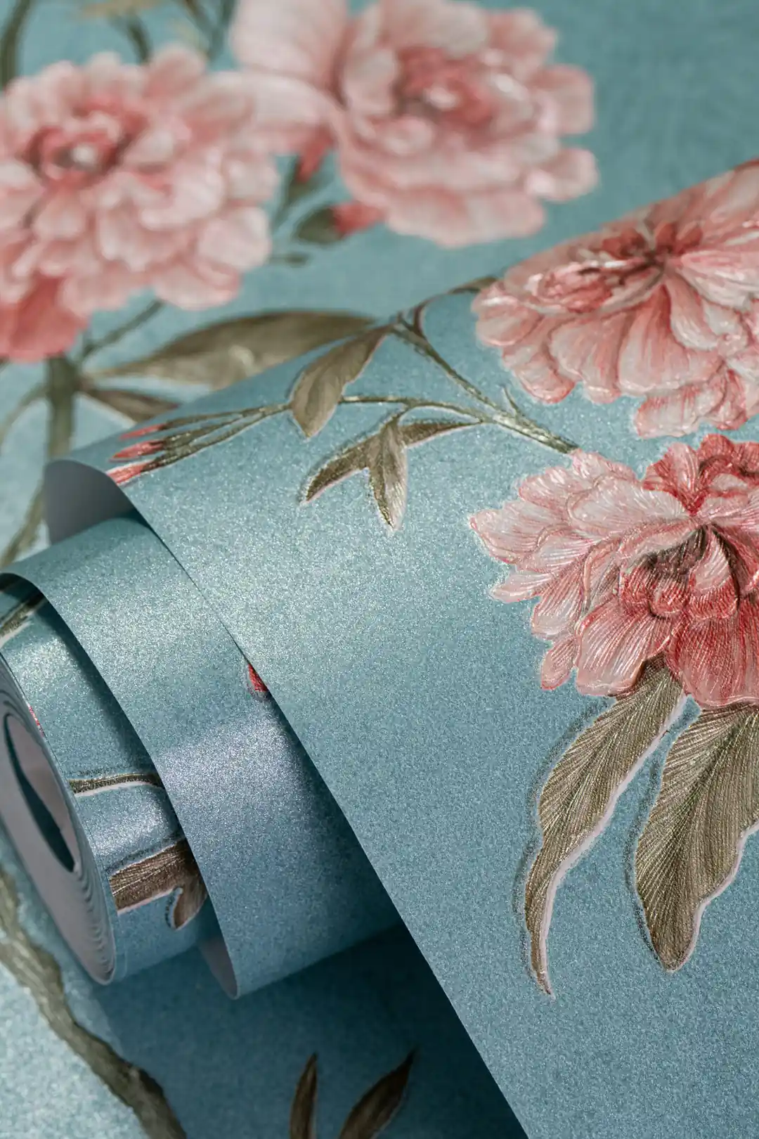Wallpaper roll with pink peony roses on a teal blue shimmer base showing floral detail
