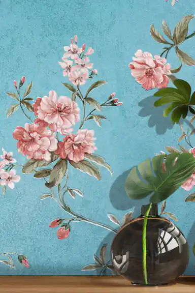 Close-up of pink peony bouquet and blossoms on teal blue wallpaper with glass vase and monstera leaf