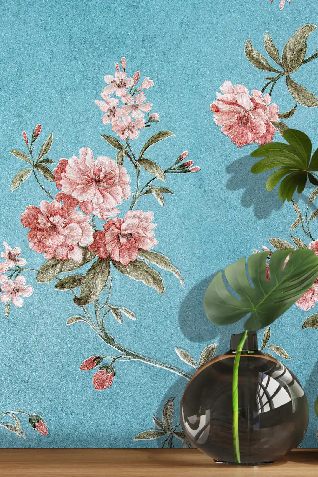 Close-up of pink peony bouquet and blossoms on teal blue wallpaper with glass vase and monstera leaf