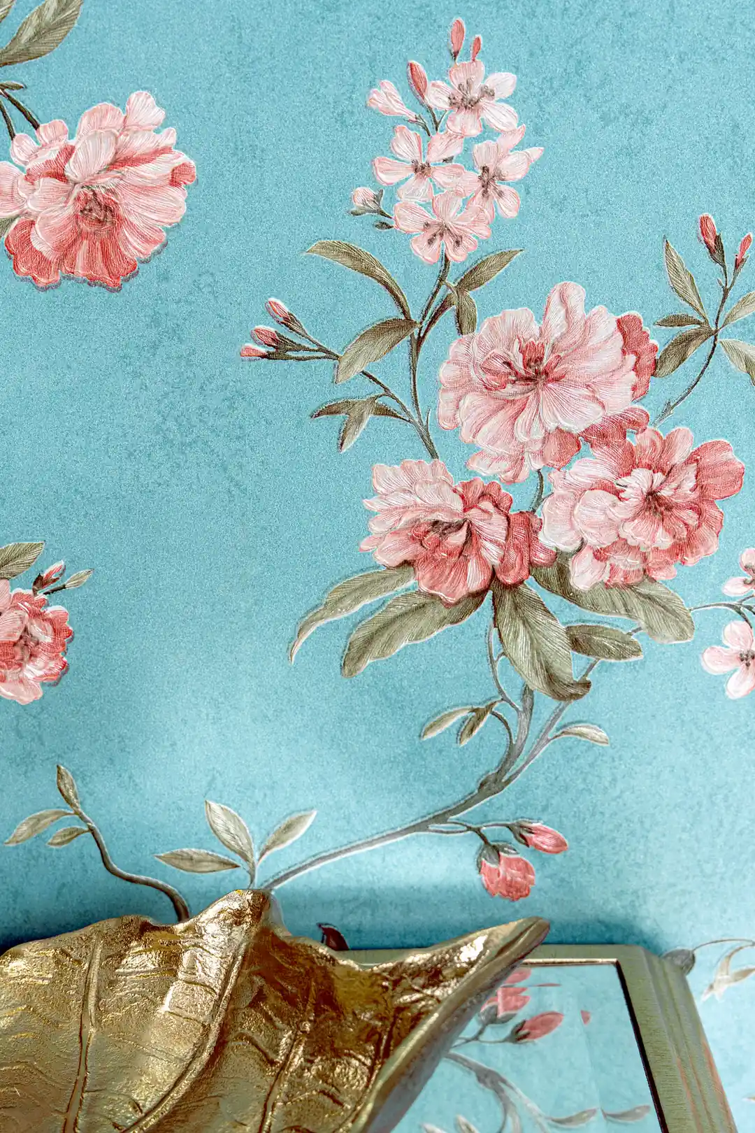 Detailed view of pink peony bloom clusters on teal blue wallpaper with gold decorative accent