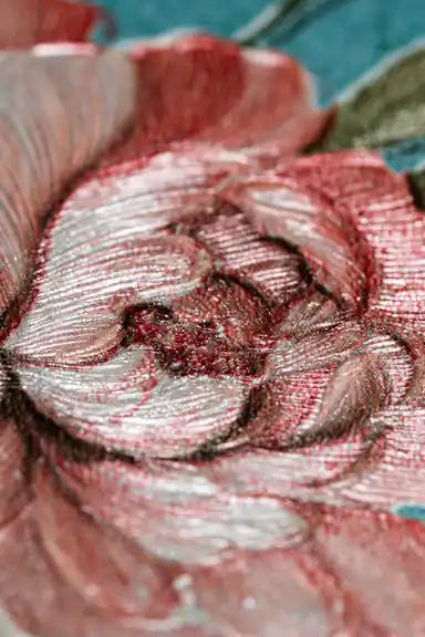 Extreme close-up macro of embossed pink peony petals showing fine texture on teal blue base