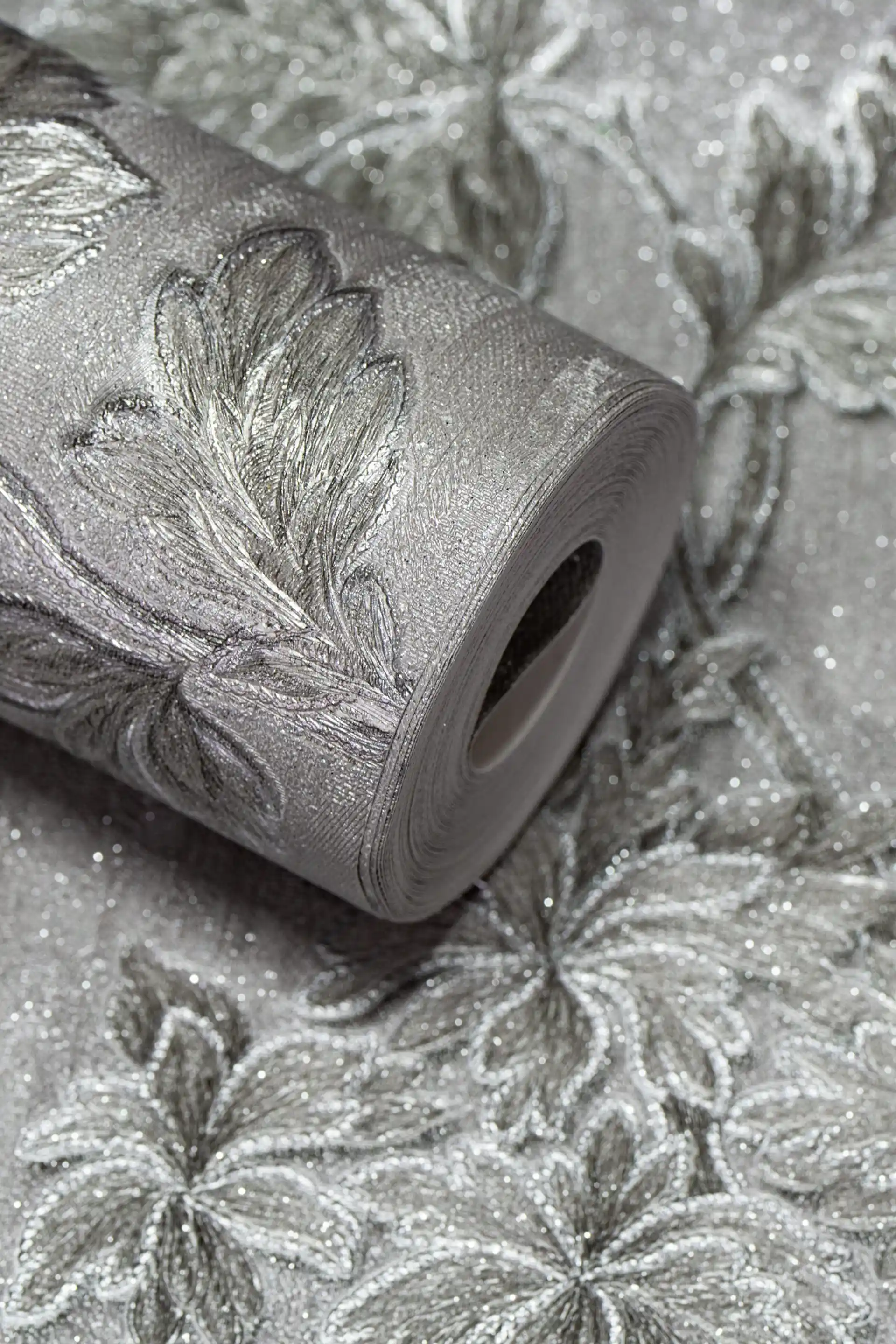 Silver wallpaper roll with embossed floral vine pattern and sparkling glitter finish