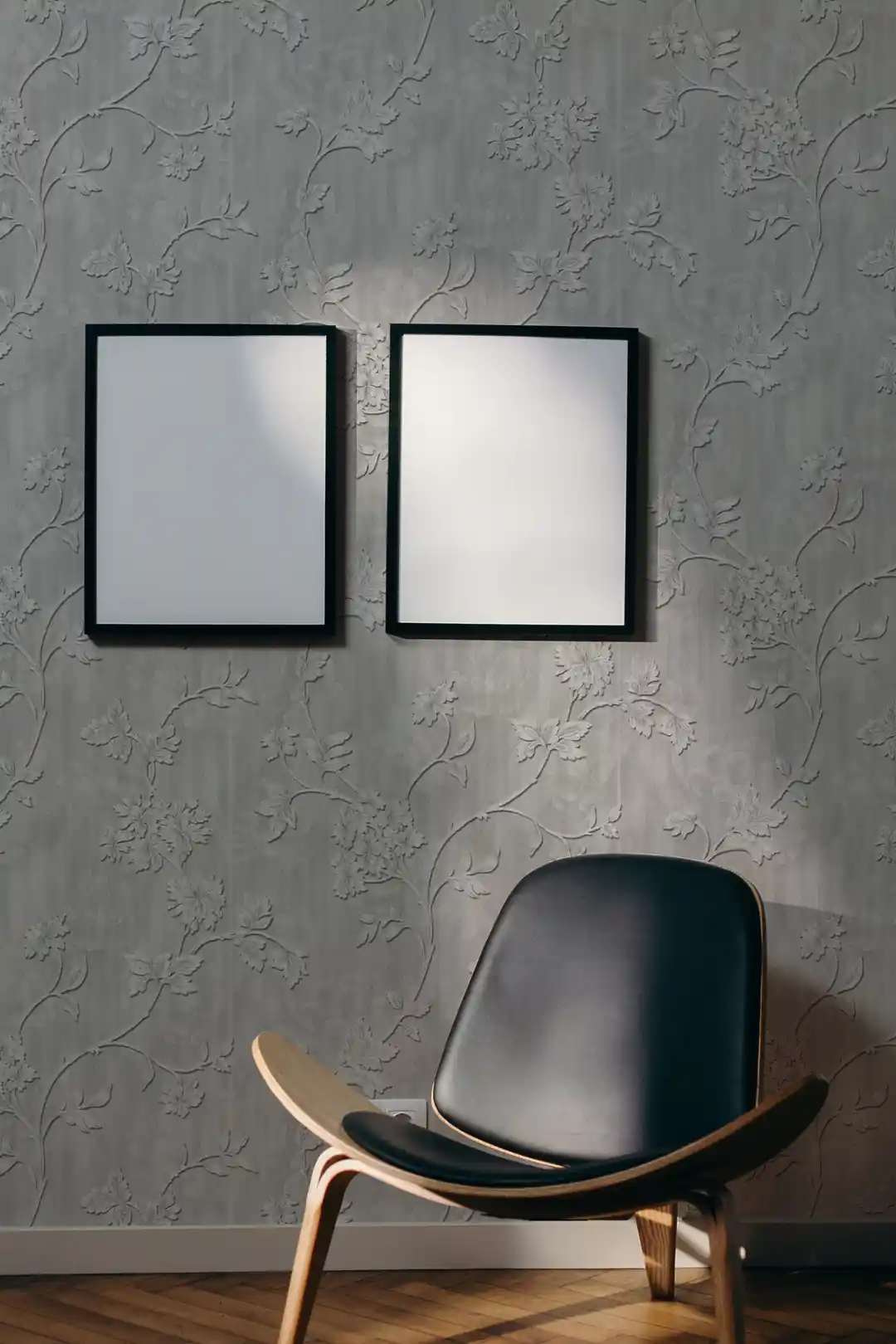 Modern living room with silver floral vine embossed wallpaper, dark leather shell chair, and blank white frames
