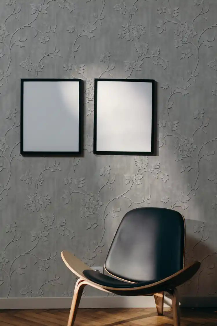 Modern living room with silver floral vine embossed wallpaper, dark leather shell chair, and blank white frames