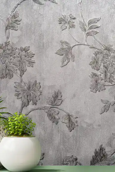Close-up of silver embossed floral vine and leaves on grey wallpaper with green plant accent