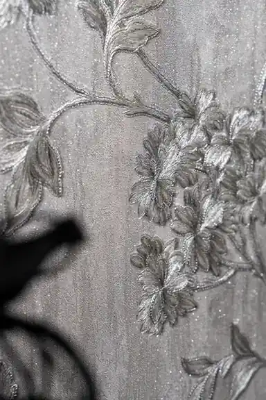 Detailed view of raised silver floral cluster with vine tendrils and glitter shimmer on grey base