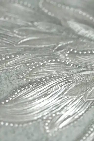 Extreme close-up of silver embossed damask leaf detail with shimmer texture on mint green base