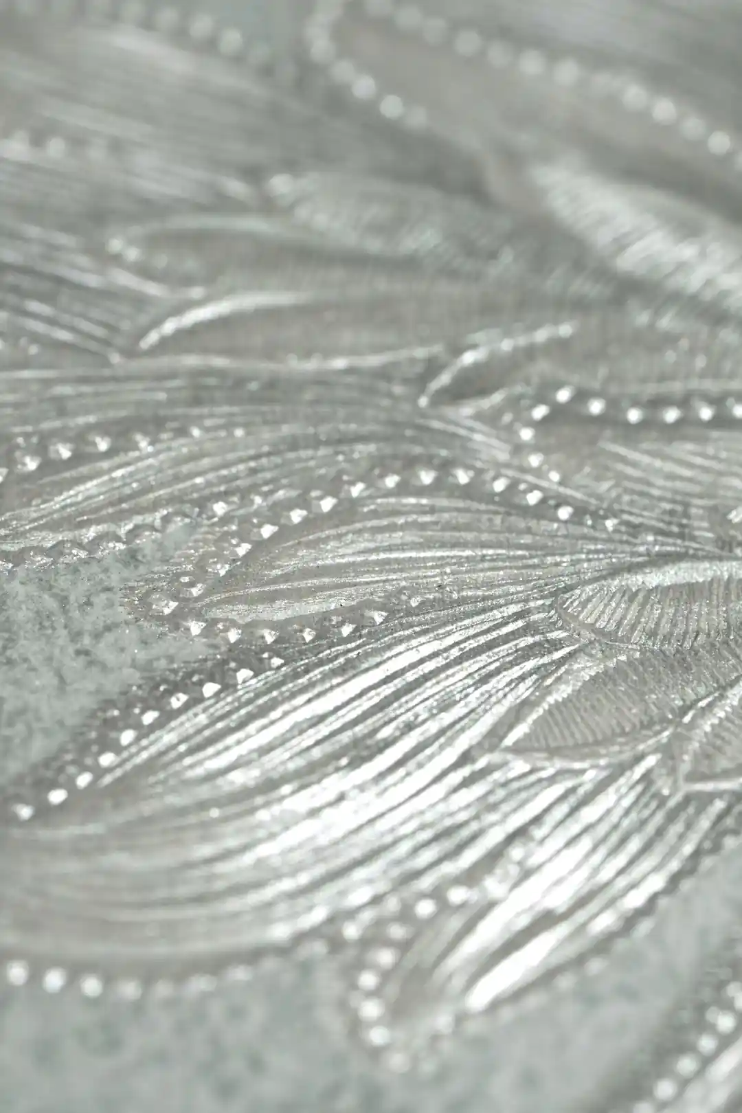 Extreme close-up of silver embossed damask leaf detail with shimmer texture on mint green base