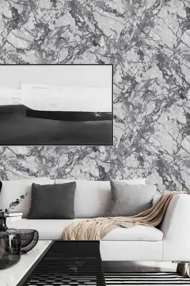 Modern living room with grey marble wallpaper behind white sofa, abstract art, and dark cushions