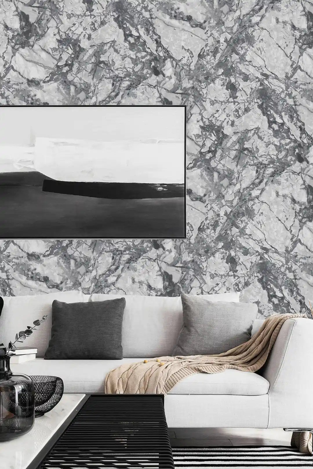 Modern living room with grey marble wallpaper behind white sofa, abstract art, and dark cushions