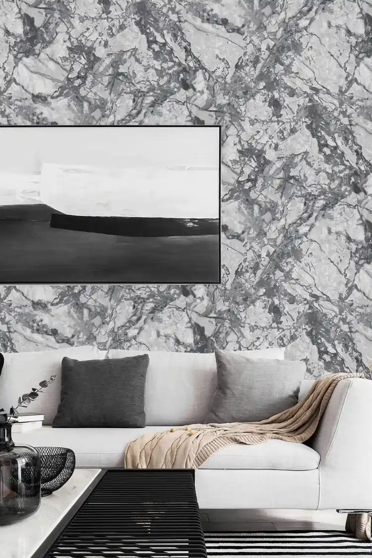 Modern living room with grey marble wallpaper behind white sofa, abstract art, and dark cushions