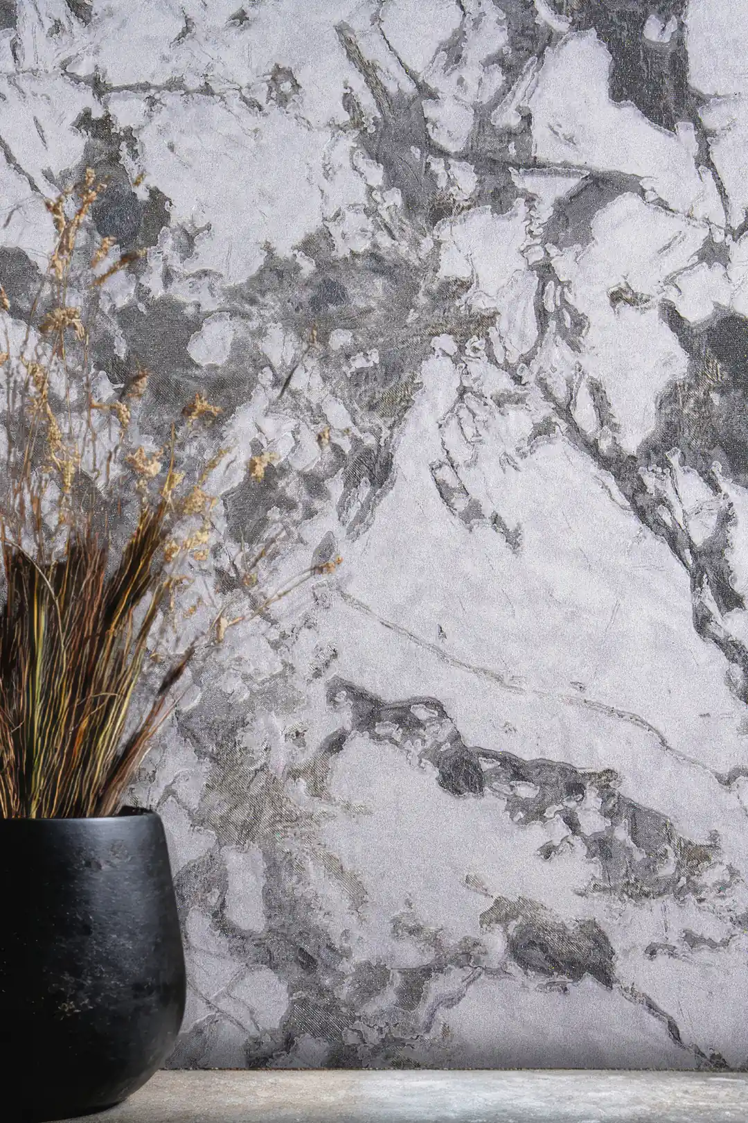 Close-up of grey and white marble veining wallpaper with black vase and dried branches