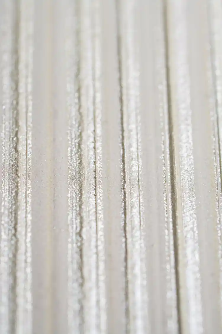 Extreme close-up of shimmer texture detail on white silk stripe wallpaper surface