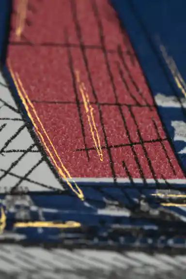 Extreme close-up of red sailboat sail texture showing embossed glitter detail on navy wallpaper
