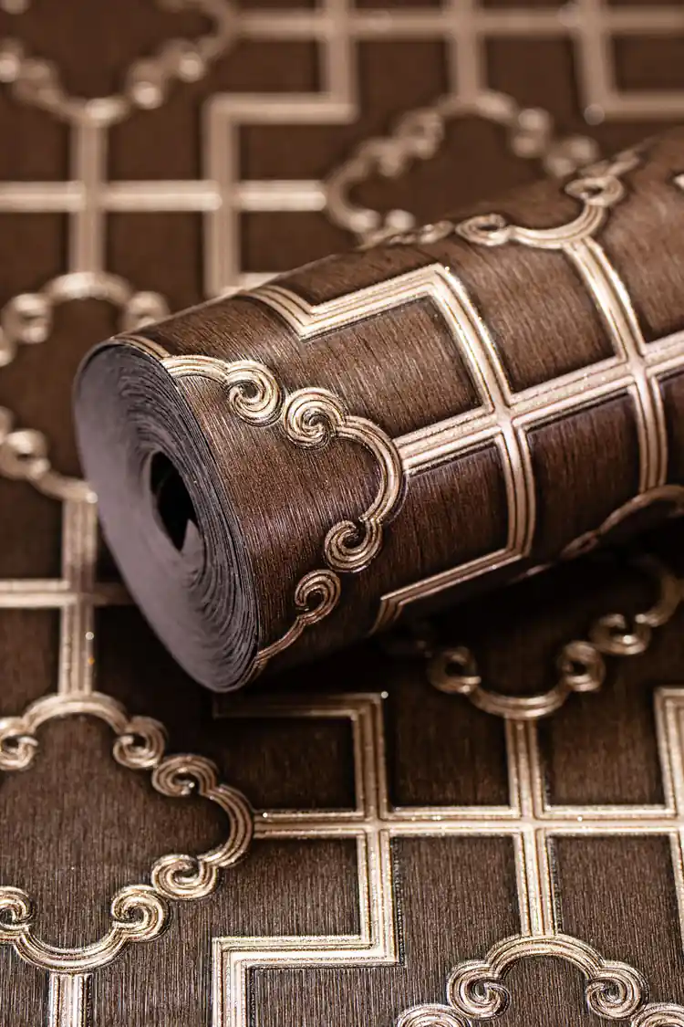 Rolled brown geometric trellis wallpaper showing embossed pattern with gold scroll accents