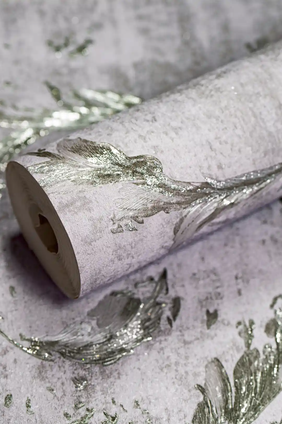 Silver leaf swirl wallpaper roll with metallic glitter finish on a grey textured base