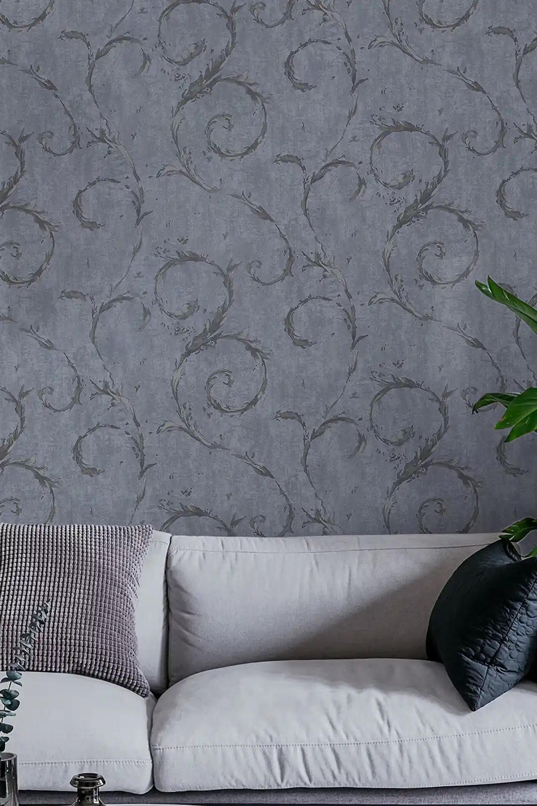 Living room with grey leaf swirl wallpaper behind a white sofa with cushions and green plant