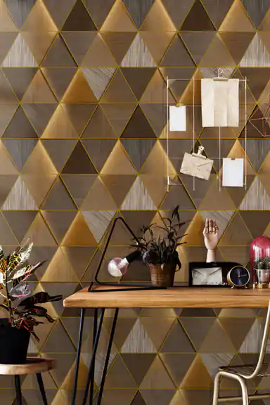 Home office with metallic gold triangle wallpaper behind wooden desk with plants and vintage decor