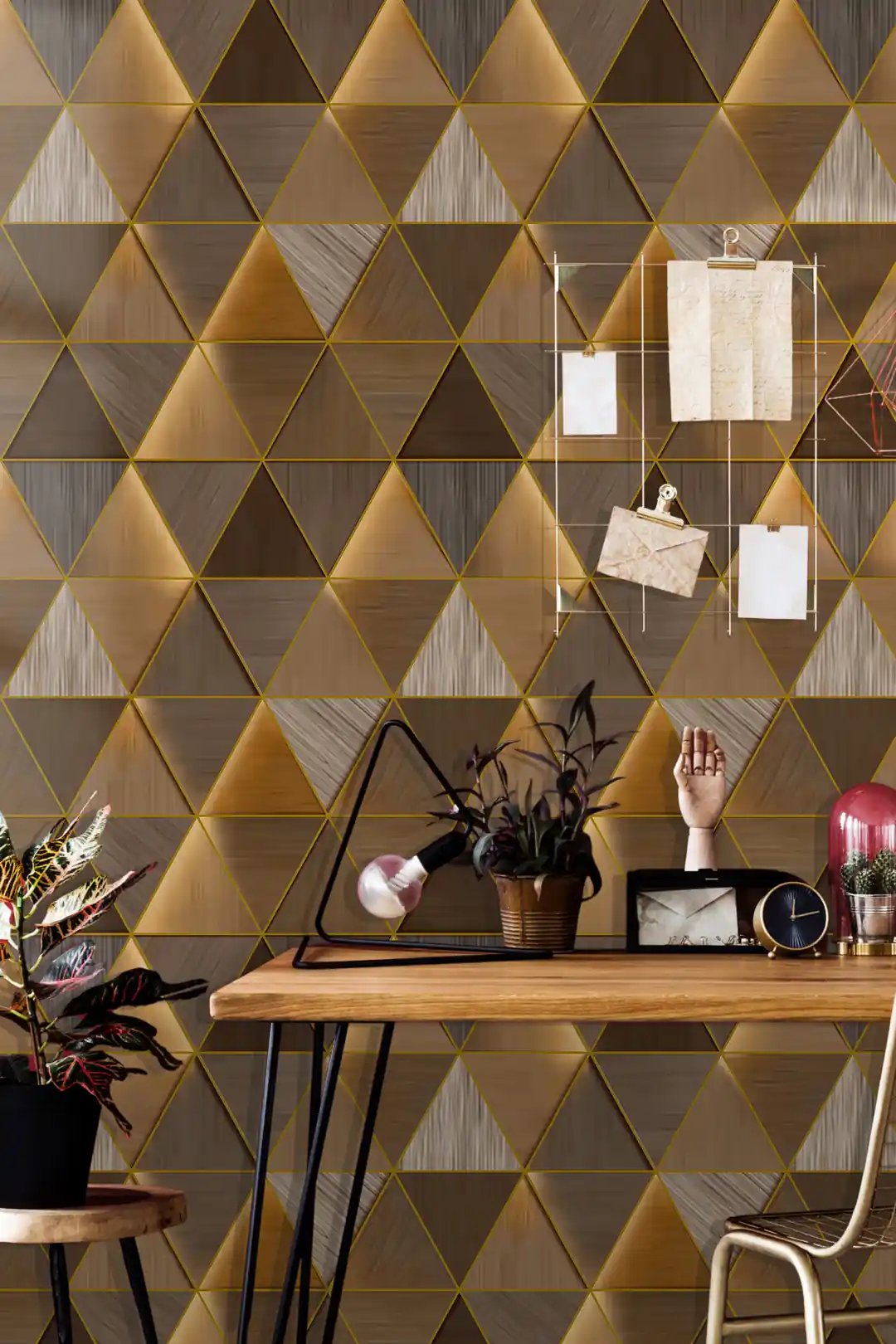 Home office with metallic gold triangle wallpaper behind wooden desk with plants and vintage decor