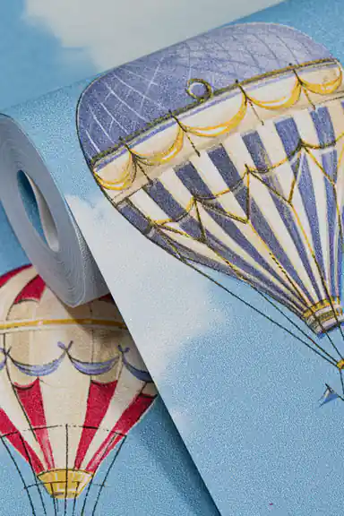 Wallpaper roll close-up showing blue and red hot air balloons on bright blue sky with clouds