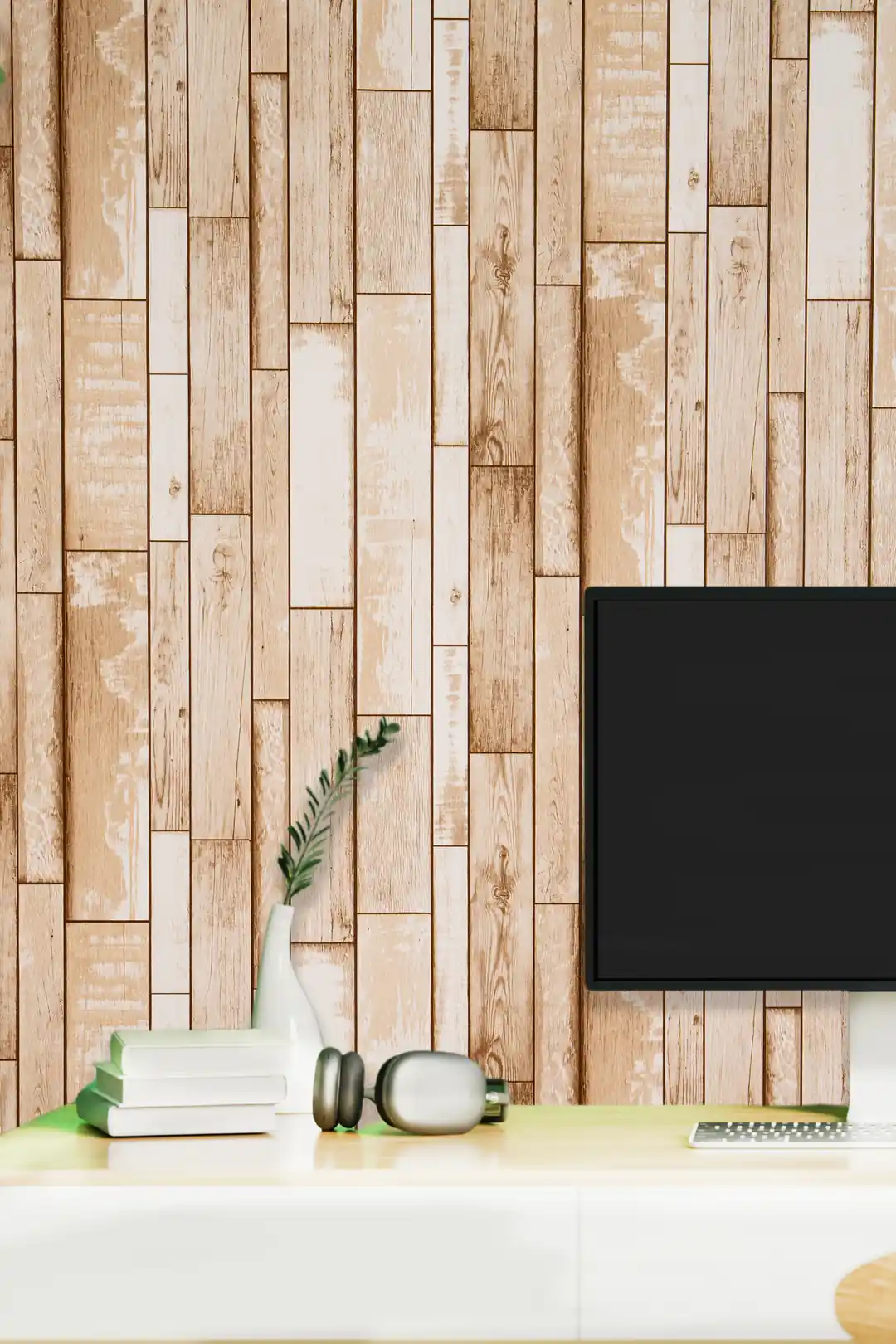Home office with beige wood plank wallpaper behind desk with monitor, plant, and headphones
