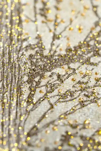 Extreme close-up macro of gold glitter particles on pine tree branches showing sparkle texture