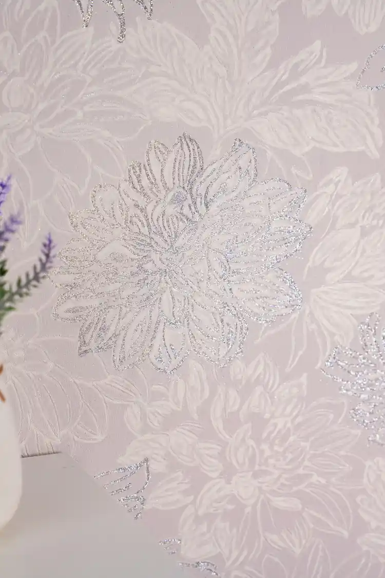 Close-up of a single silver glitter chrysanthemum bloom on soft pink embossed wallpaper
