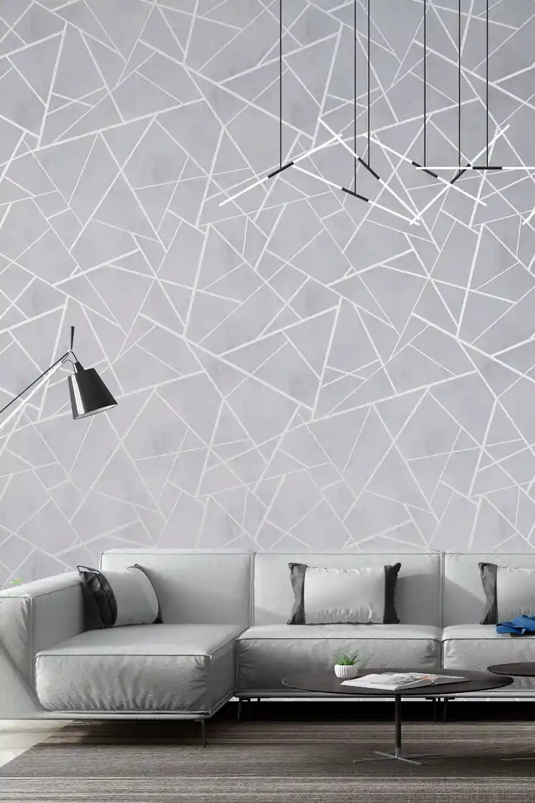 Modern living room with gray geometric wallpaper featuring silver lines behind a minimalist sofa and pendant lights