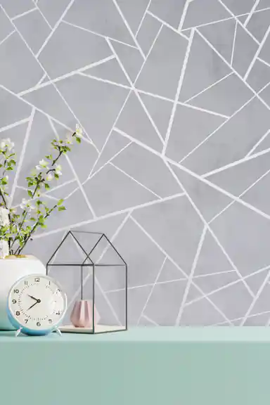 Installed gray abstract geometric wallpaper behind a mint shelf with a clock, flowers, and glass terrarium
