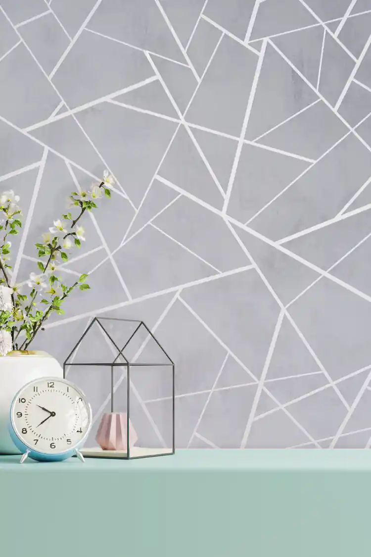 Installed gray abstract geometric wallpaper behind a mint shelf with a clock, flowers, and glass terrarium